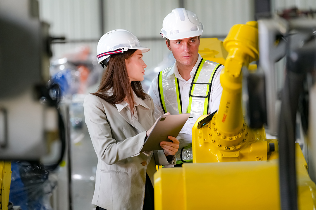 Indusrtial Robot technology, Engineers inspecting stock of welding robots at factory.