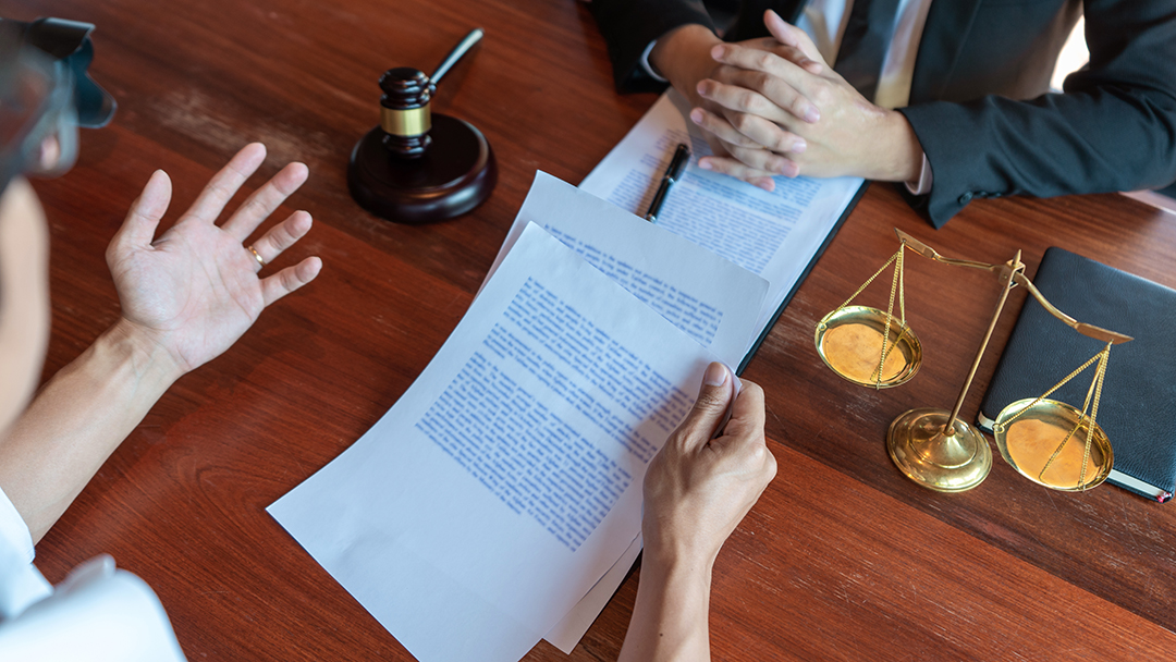 Lawyer working with client discussing contract papers with brass