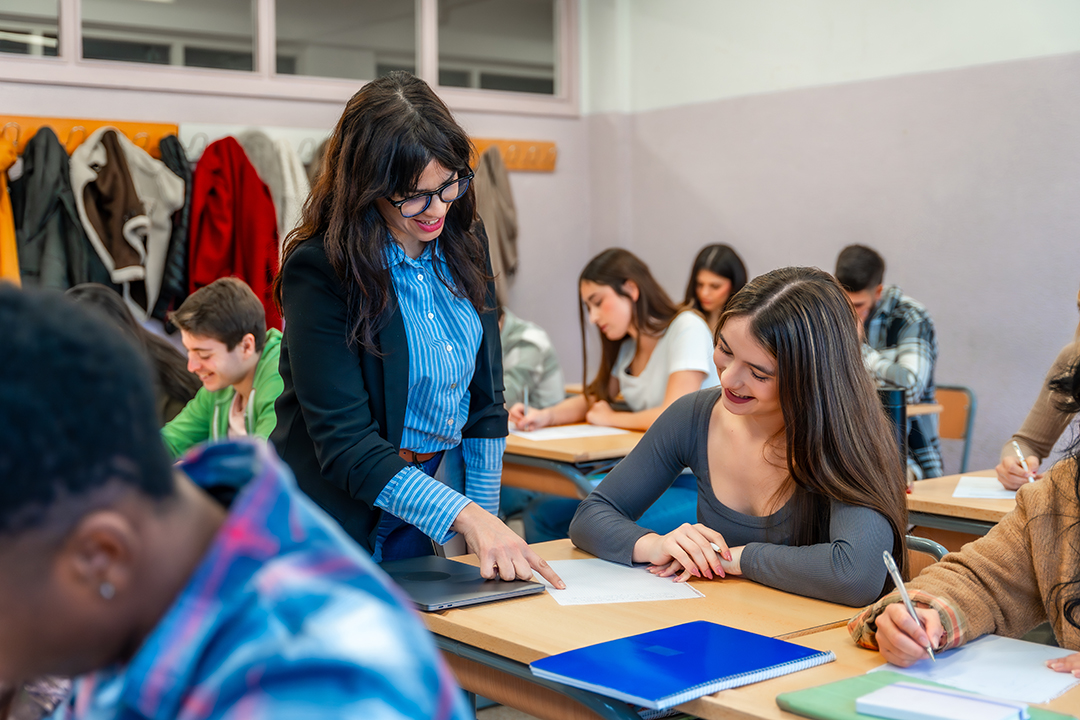 Teacher helping student during exam in university classroom